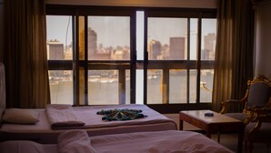 A hotel room with two beds, a small table, and a chair. - Nile sky hotel and suites (Cairo)