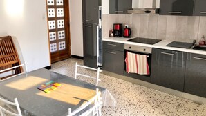 Une cuisine moderne équipée d’un réfrigérateur, d’une machine à café et d’une table à manger avec des chaises.