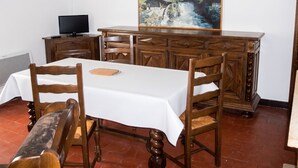 Un coin repas avec une table blanche, des chaises en bois, un buffet en bois et un tableau représentant un paysage de montagne.