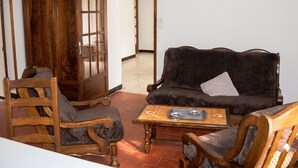 Un salon avec un meuble en bois, un canapé marron foncé et une chaise en bois.