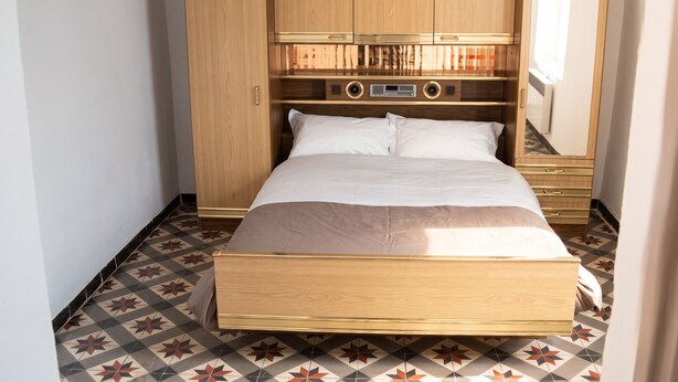 Une chambre à coucher avec un lit, une armoire en bois et un miroir.