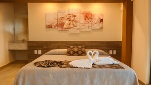 A hotel room with a bed, a nightstand, a wall-mounted artwork, and a bathroom visible in the background. - Hotel Casa Ixtapa (Ixtapa)
