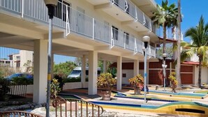 A hotel with multiple balconies, a pool area with a wooden bridge, and palm trees. - Hotel Casa Ixtapa (Ixtapa)