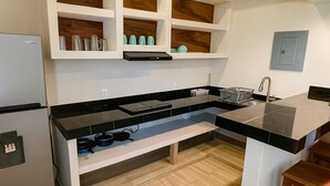 A modern kitchen with white cabinetry, a built-in oven, and a black countertop. - Hotel Casa Ixtapa (Ixtapa)