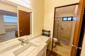 A bathroom with a marble sink, a glass shower enclosure, and a visible toilet. - Hotel Casa Ixtapa (Ixtapa)