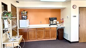 Una kitchenette pequeña con cafetera, refrigerador y un basurero.