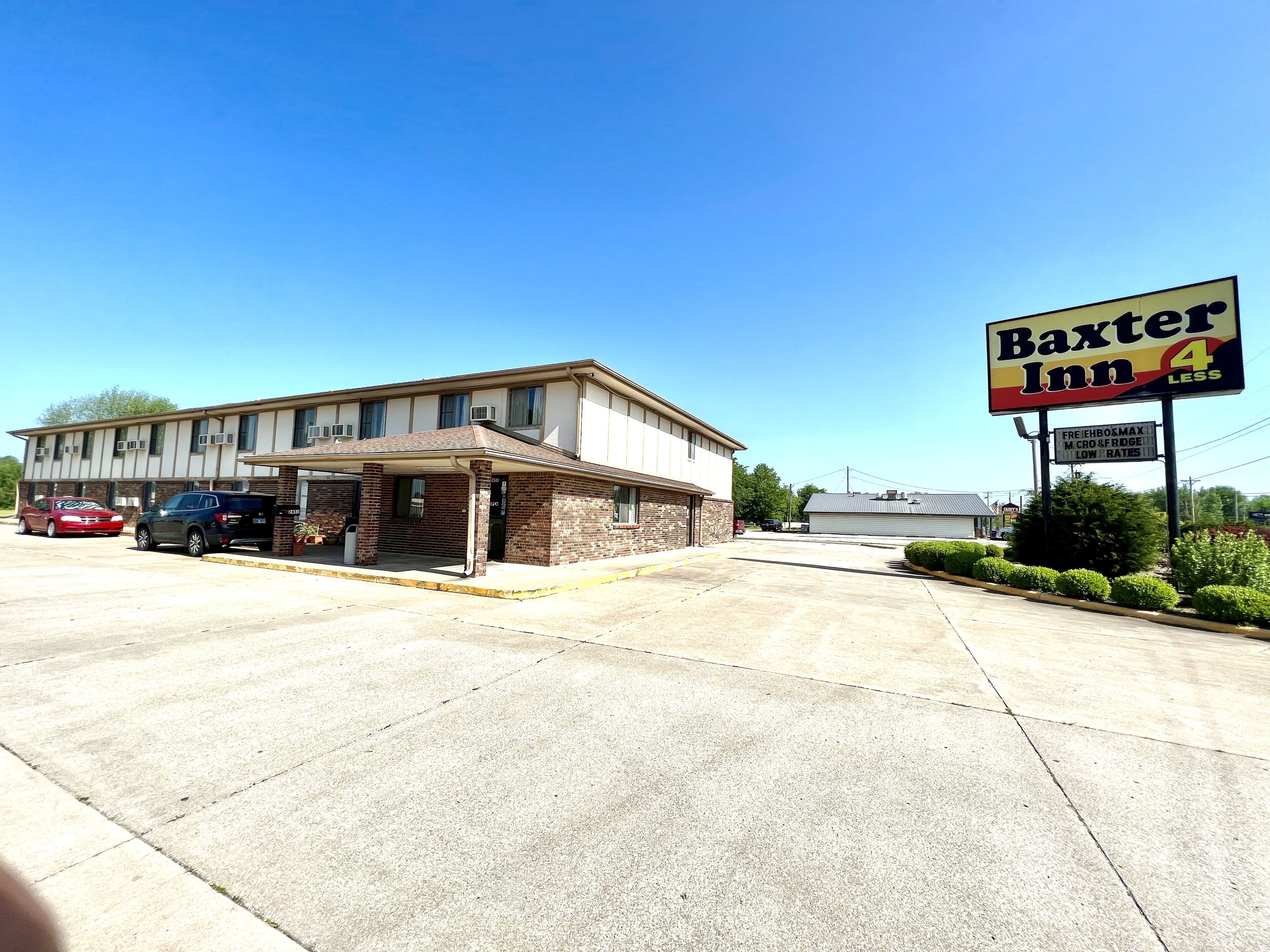 Un motel con área de estacionamiento techada y un letrero que anuncia 'Baxter Inn 4 Less'.