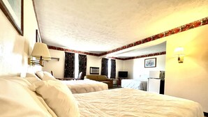 Una habitación de hotel con dos camas, un escritorio, un televisor y un refrigerador.