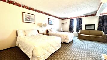 A hotel room with two beds, a sofa, a desk, and a chair.
