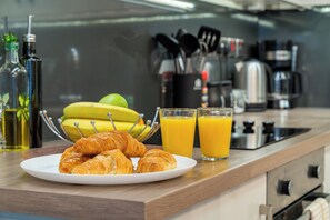 A breakfast setting with croissants, bananas, and orange juice on a kitchen counter.