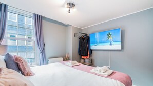 A modern bedroom with a large bed, a TV on the wall, and a window with curtains. - London Street, Andover, Hampshire, SP102NU, United Kingdom (Andover)