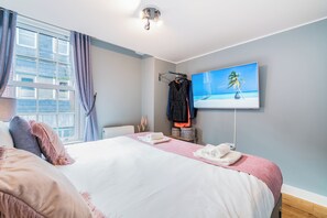 A hotel room with a bed, a TV on the wall, and a window with curtains. - London Street, Andover, Hampshire, SP102NU, United Kingdom (Andover)