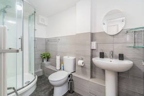 A modern bathroom with a glass shower enclosure, a toilet, a sink, and a mirror. - London Street, Andover, Hampshire, SP102NU, United Kingdom (Andover)