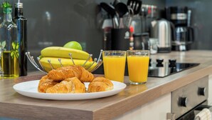 A breakfast setting with croissants on a plate, a bowl of bananas, and two glasses of orange juice on a kitchen counter. - London Street, Andover, Hampshire, SP102NU, United Kingdom (Andover)