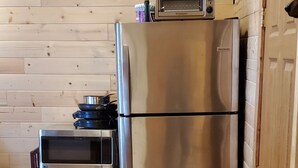 A kitchen with wooden cabinetry, a stainless steel refrigerator, a microwave, and a toaster oven. - Baby Bear Kenai/Soldotna fishing cabin- sleeps 3 - Alaska Building a Dream (Soldotna)