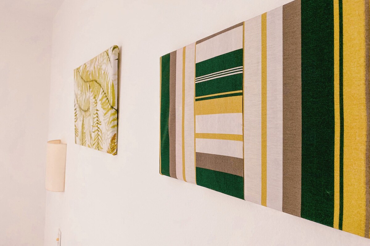 A wall with two artworks and a lamp.