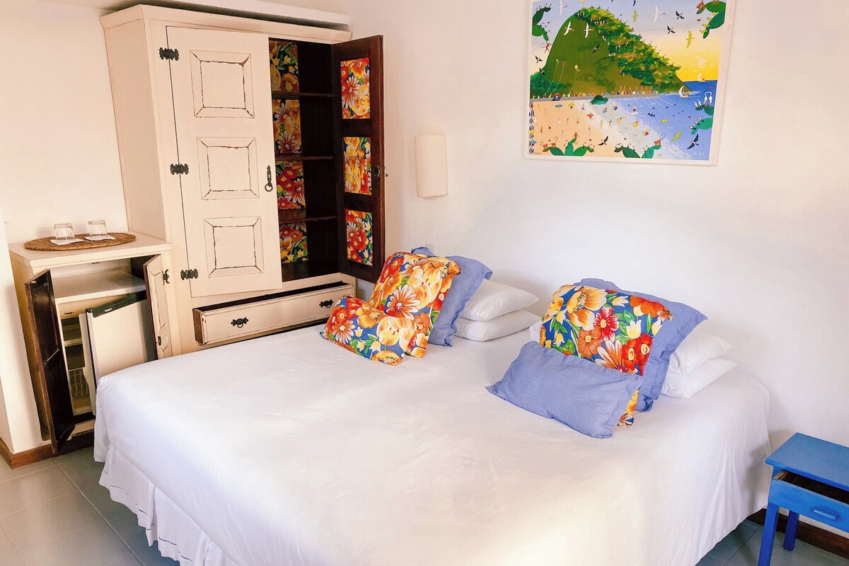 A bedroom with a bed, pillows, a wardrobe, and a painting on the wall.