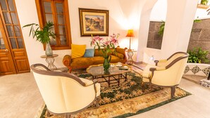 Un salón con sofá, dos sillones, una mesa de centro, una lámpara y un cuadro en la pared.