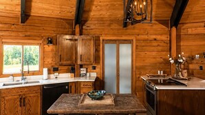 A rustic wooden cabin interior with a kitchen, dining area, and a large window. - Unique Home Where The Buffalo Roam! Perfect for Families, Reunions. Hunters. (Buffalo Ridge)