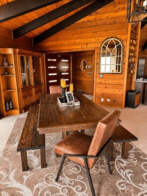 Ein Esszimmer mit Holzboden, einem großen Tisch, Stühlen und einer Deckenleuchte.