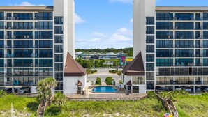 A modern hotel with a central pool, multiple balconies, and a view of surrounding buildings. - 1st Floor ~ Pet Friendly ~ Fall Specials! Free Beach Chair Service! (Panama City Beach)