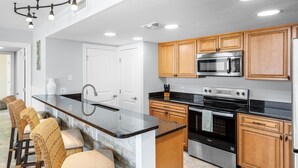 A modern kitchen with a central island, stainless steel appliances, and wooden cabinets. - 1st Floor ~ Pet Friendly ~ Fall Specials! Free Beach Chair Service! (Panama City Beach)