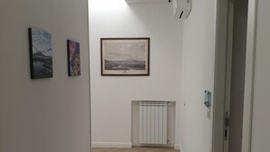 Un pasillo con suelo de madera, paredes blancas y un cuadro en la pared.