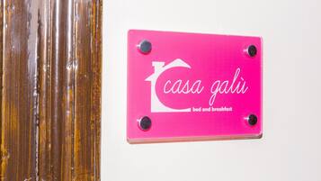 En rosa skylt med texten ”casa gali bed and breakfast” som är fastsatt på en vägg.