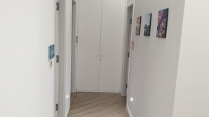 Un pasillo con suelo de madera, paredes blancas y una puerta al final. Hay tres obras de arte en la pared.