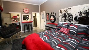 A bedroom with a bed, a desk, and a chair. There is a door leading to another room.