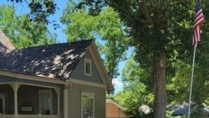 A residential area with a house and a sign that reads "GARDEN OF THE MONTH."
