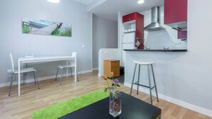 Une cuisine moderne avec des meubles rouges, une hotte en acier inoxydable et un réfrigérateur blanc.