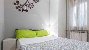 Une chambre à coucher avec un lit, un radiateur et une fenêtre avec des rideaux.