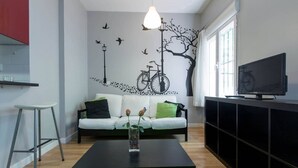 Un salon moderne avec un canapé blanc, une table basse noire et un téléviseur posé sur un meuble noir.