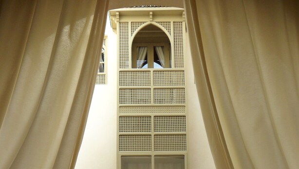 A room with a high arched window, two chairs, a small table with a decorative item, and a large rug on the floor. - RIAD ET SPA MISRIA LES OLIVIERS (Marrakech)