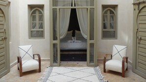 A room with a bed centered between two windows, flanked by two chairs. - RIAD ET SPA MISRIA LES OLIVIERS (Marrakech)