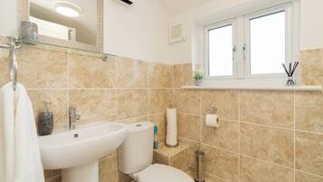 A bathroom with a sink, toilet, and a window above the toilet.