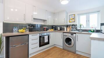 A modern kitchen with white cabinets, stainless steel appliances, and a wooden countertop.