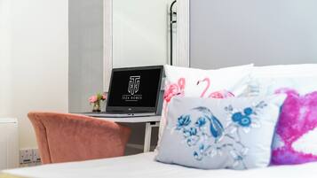 A hotel room with a bed, a desk with a laptop, and a chair.