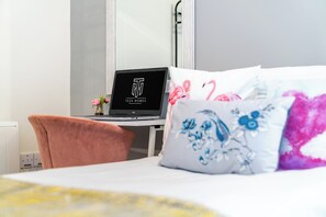 Ein Hotelzimmer mit einem Bett, einem Schreibtisch mit einem Laptop und einem Sessel.