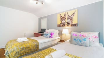 Habitación de hotel con dos camas, un escritorio, una computadora portátil y un cuadro de burros en la pared.