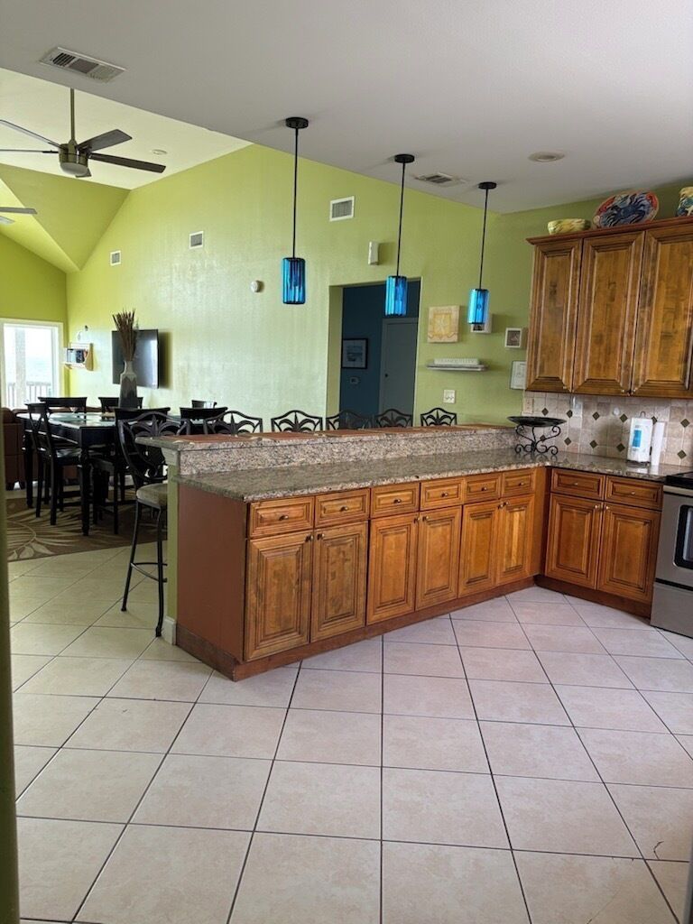 A kitchen with a large island, wooden cabinets, and pendant lights.