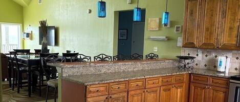 A kitchen with a large island, wooden cabinets, and pendant lights.