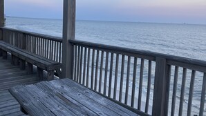 A wooden deck with a railing overlooking a calm sea.