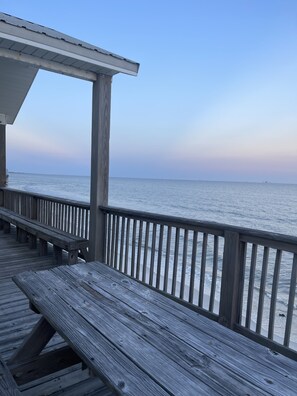 A wooden deck with a railing overlooking a calm sea.