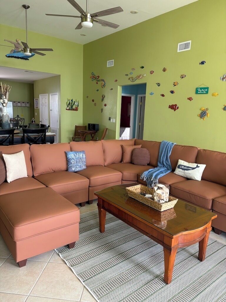 A living room with a sectional sofa, a coffee table, and a ceiling fan.