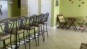 A dining area with a high ceiling, ceiling fan, and decorative wall art.