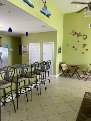 A dining area with a high ceiling, ceiling fan, and decorative wall art.