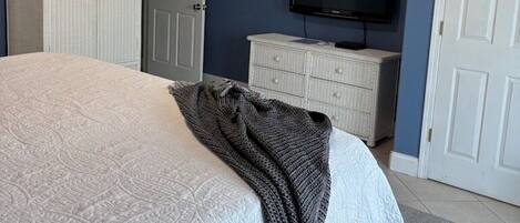 A bedroom with a bed, a television, a wardrobe, and a ceiling fan.