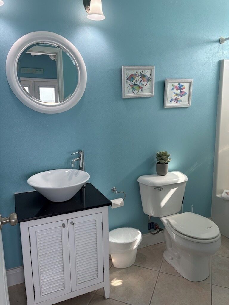 A bathroom with a white sink, a toilet, and a bidet. There are two framed pictures on the wall.